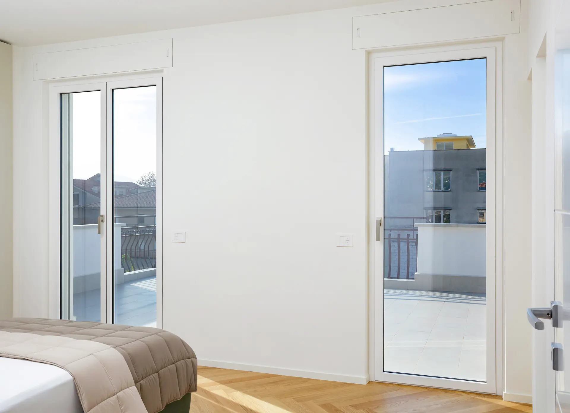 Serramenti Ponzio WS65AS Bianco Opaco - Camera da Letto con Parquet Coppia di portefinestre Ponzio WS65AS a 1 e 2 ante, finitura bianco opaco, in camera da letto moderna con parquet.