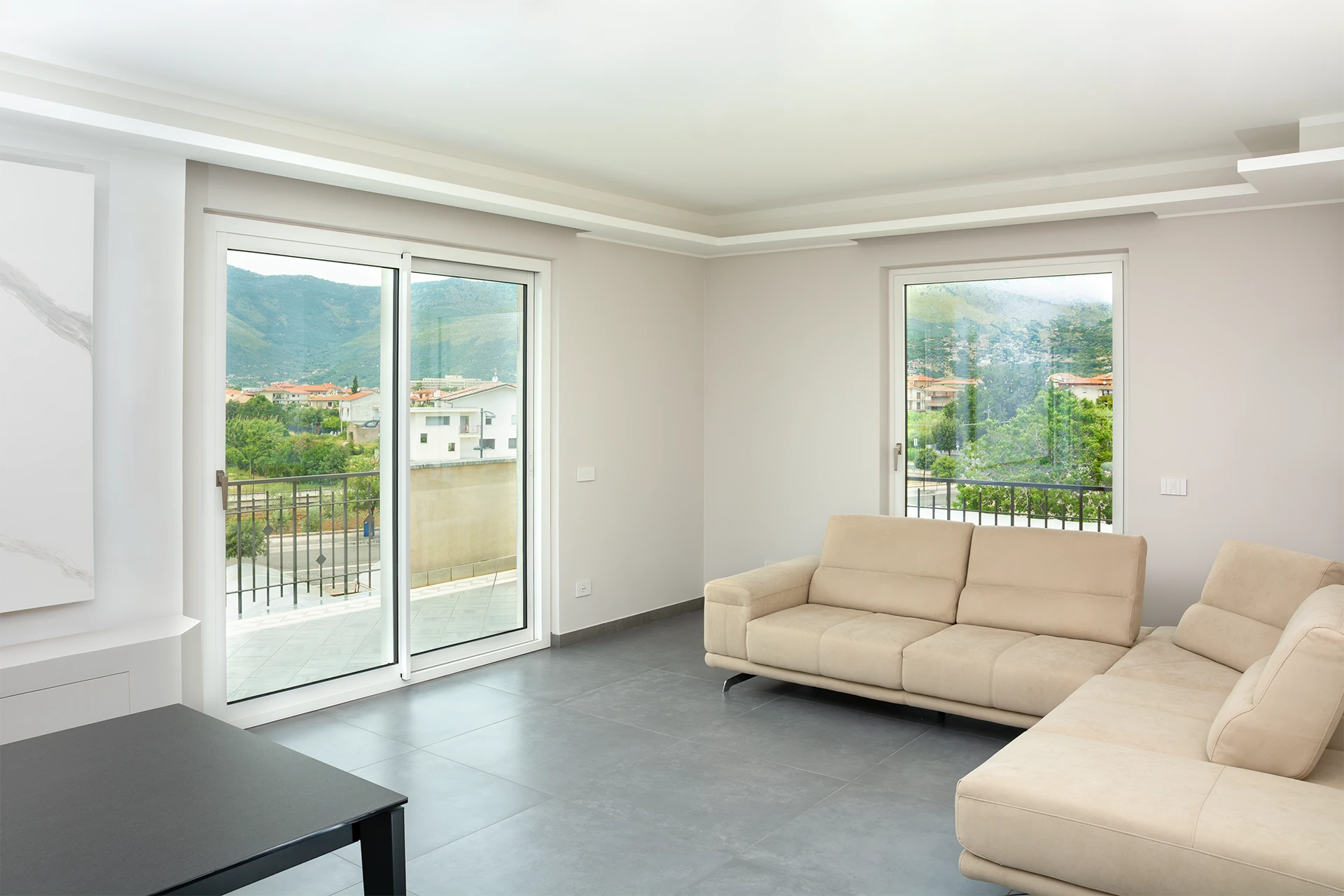 Living Moderno | Scorrevole Bianco Opaco e Finestra Panoramica Ampia sala moderna con divano ad angolo, caratterizzata da uno scorrevole Ponzio a due ante bianco opaco e una grande finestra ad anta singola con vista su montagne